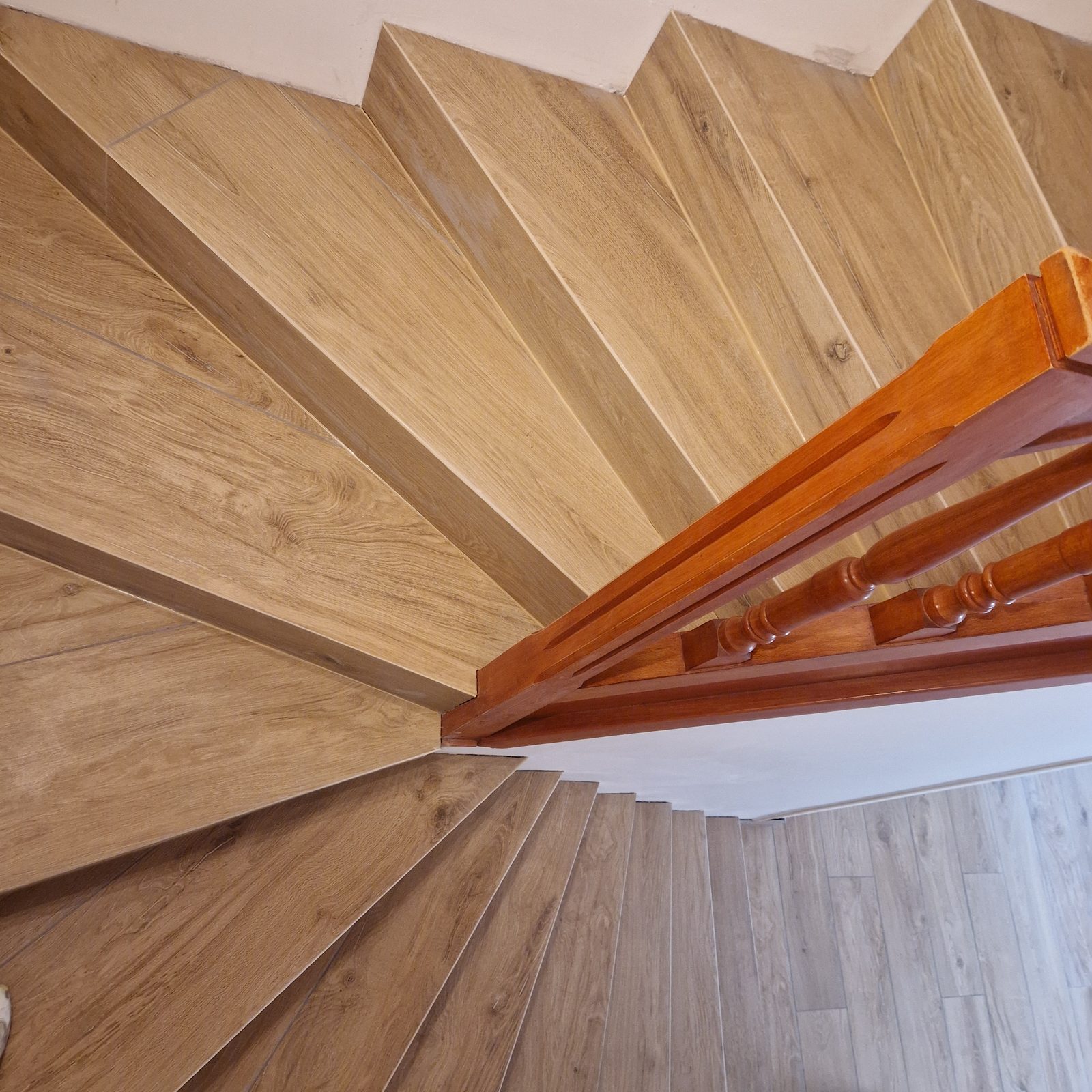 Vue de dessus d'un escalier tournant carrelé effet bois avec marches en éventail