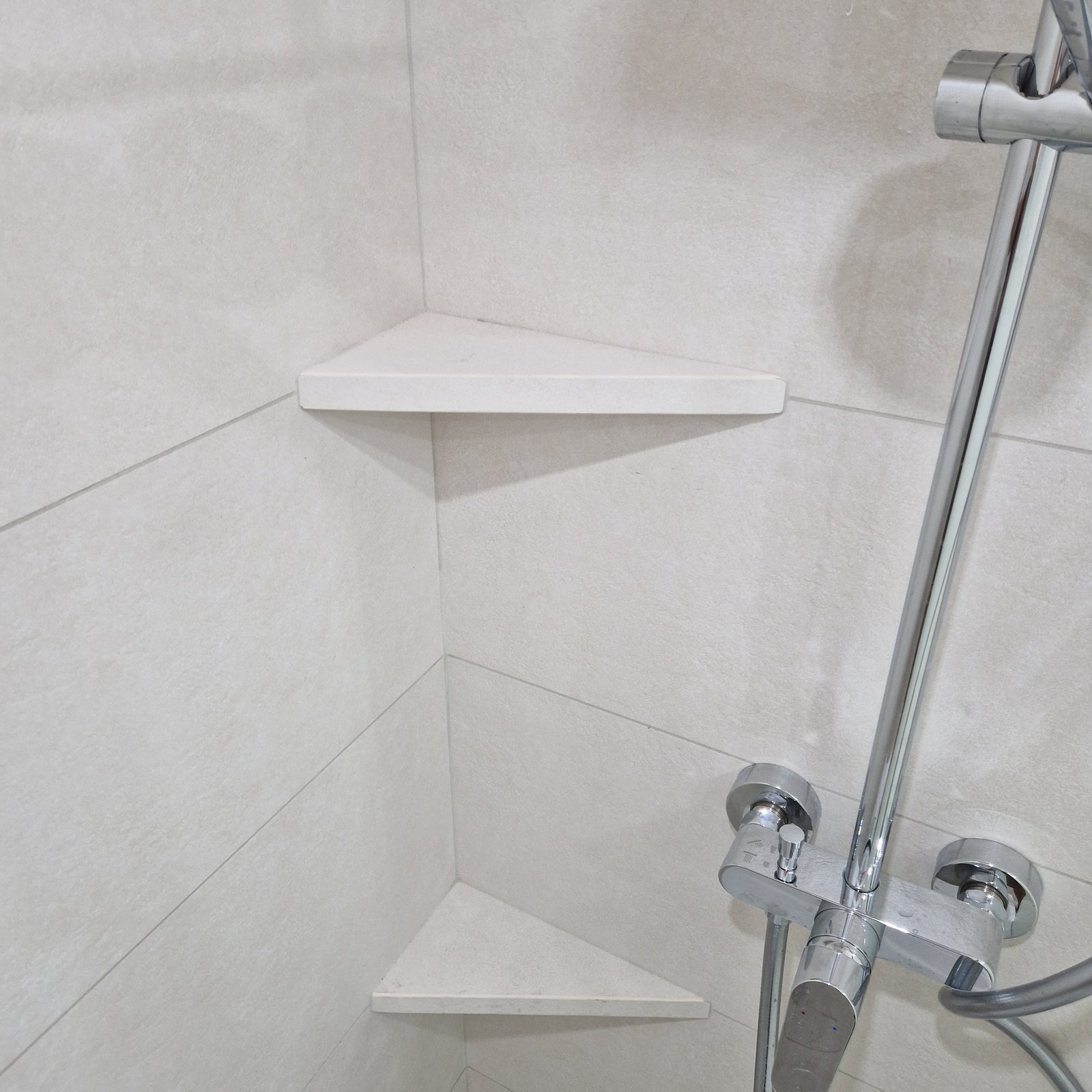Douche à l'italienne avec étagères d'angle en pierre, parois en grand format clair, réalisée à Meylan dans le Grésivaudan