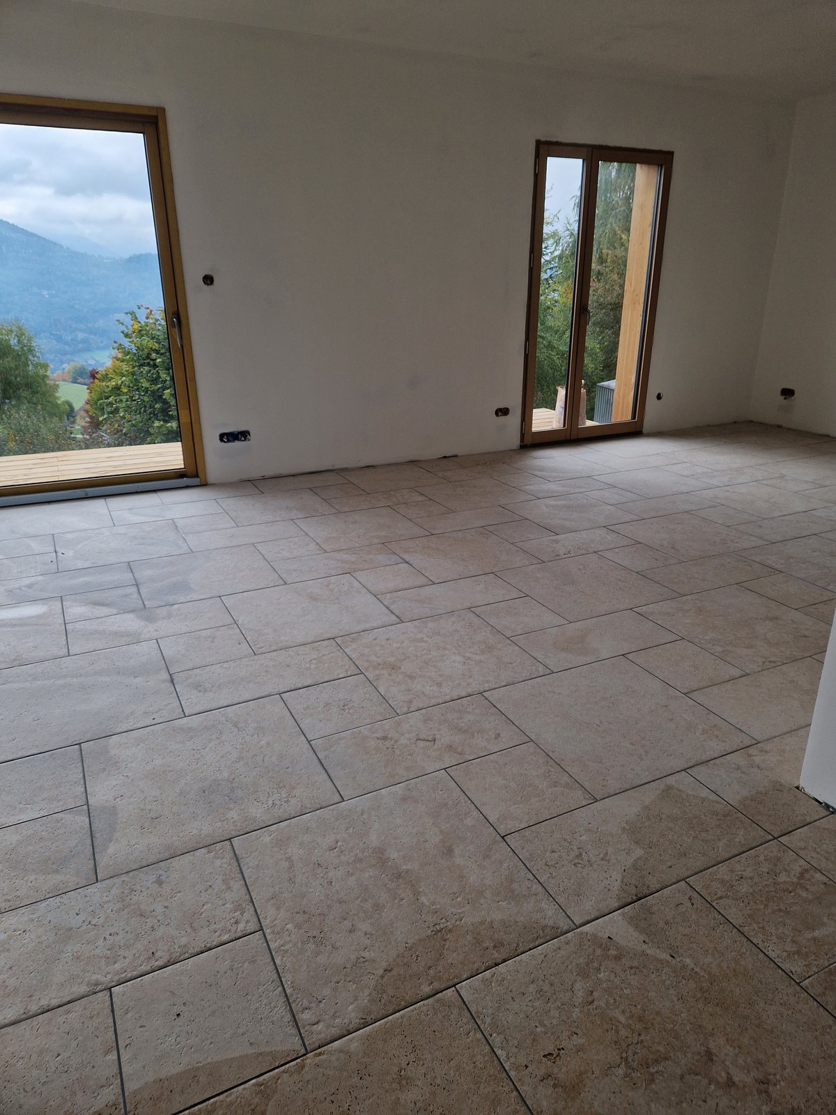 Sol en travertin posé en opus romain dans une grande pièce de vie avec vue montagne, projet réalisé en Isère