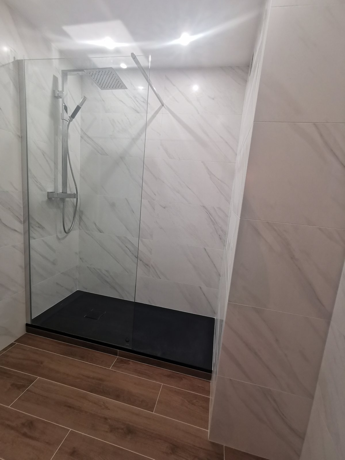Après : douche à l'italienne avec carrelage effet marbre clair, receveur extra-plat anthracite, paroi vitrée