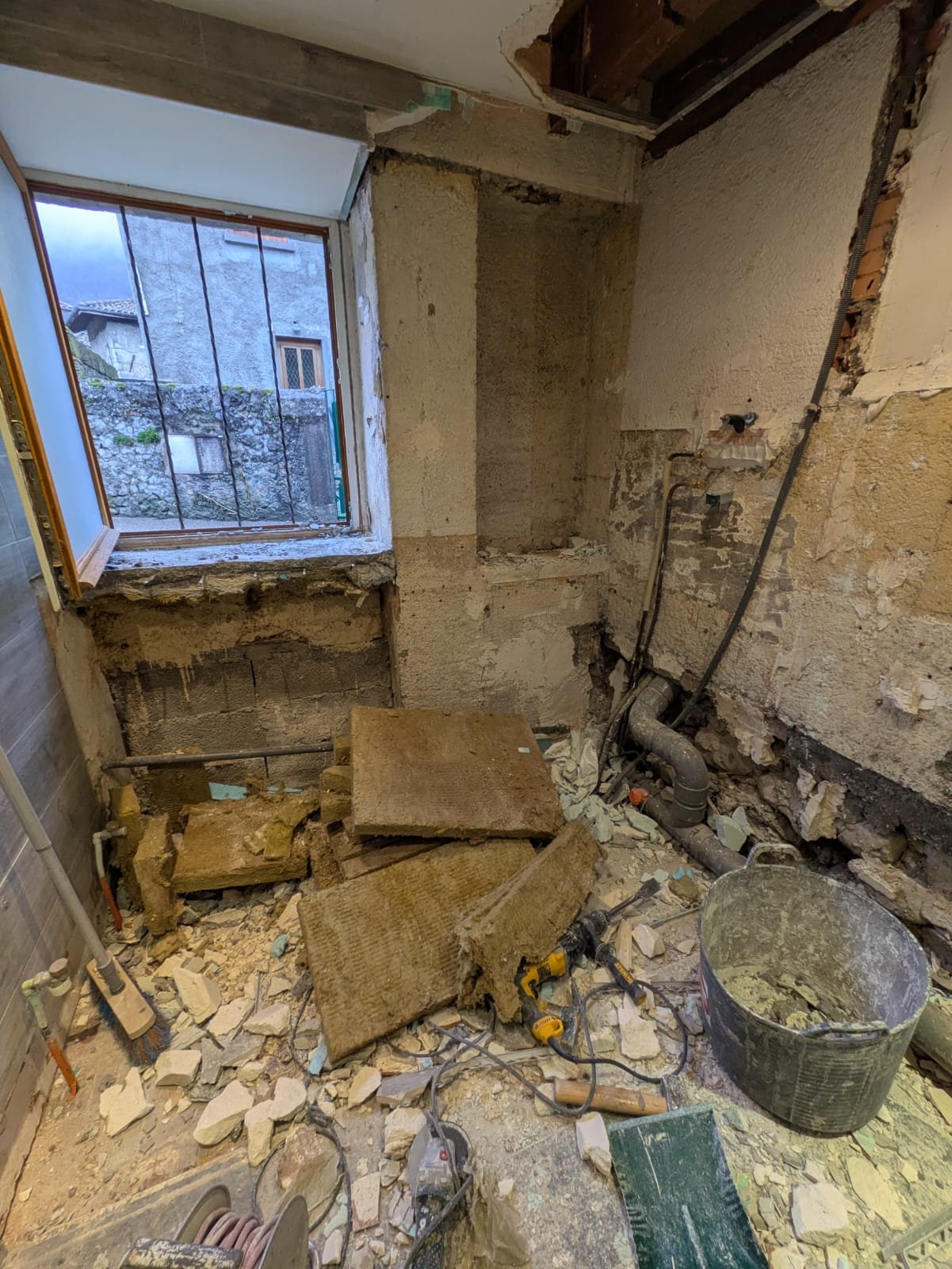 Avant : salle de bain en démolition complète, gravats au sol, plomberie et évacuations à reprendre