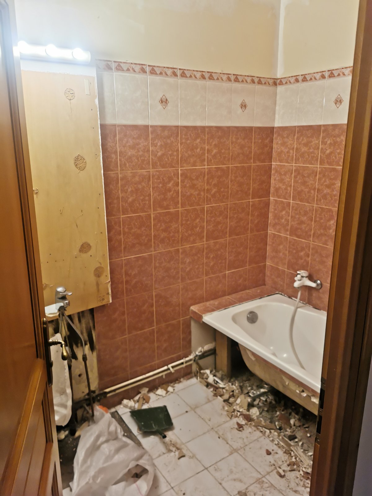 Avant : ancienne salle de bain avec faïence orange et baignoire, démolition partielle