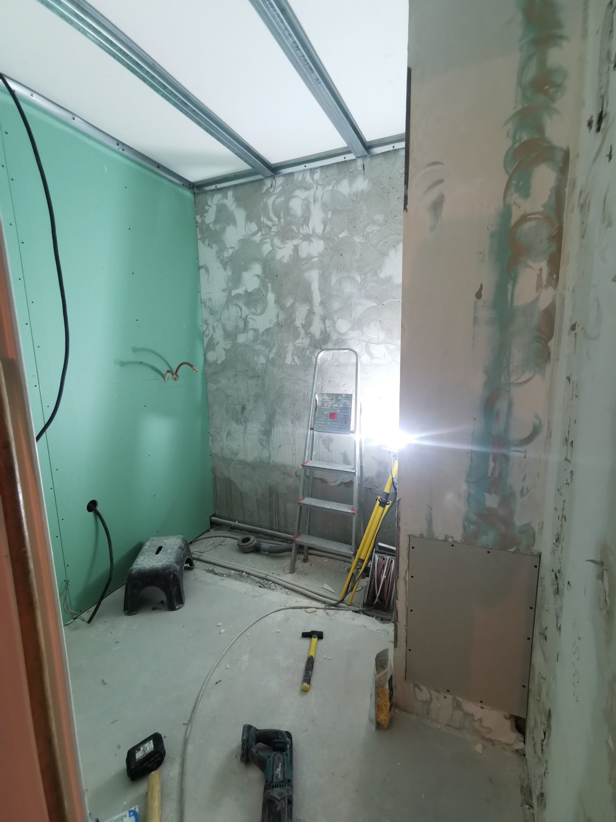 Avant : pièce en cours de démolition, anciennes peintures vertes, plomberie apparente