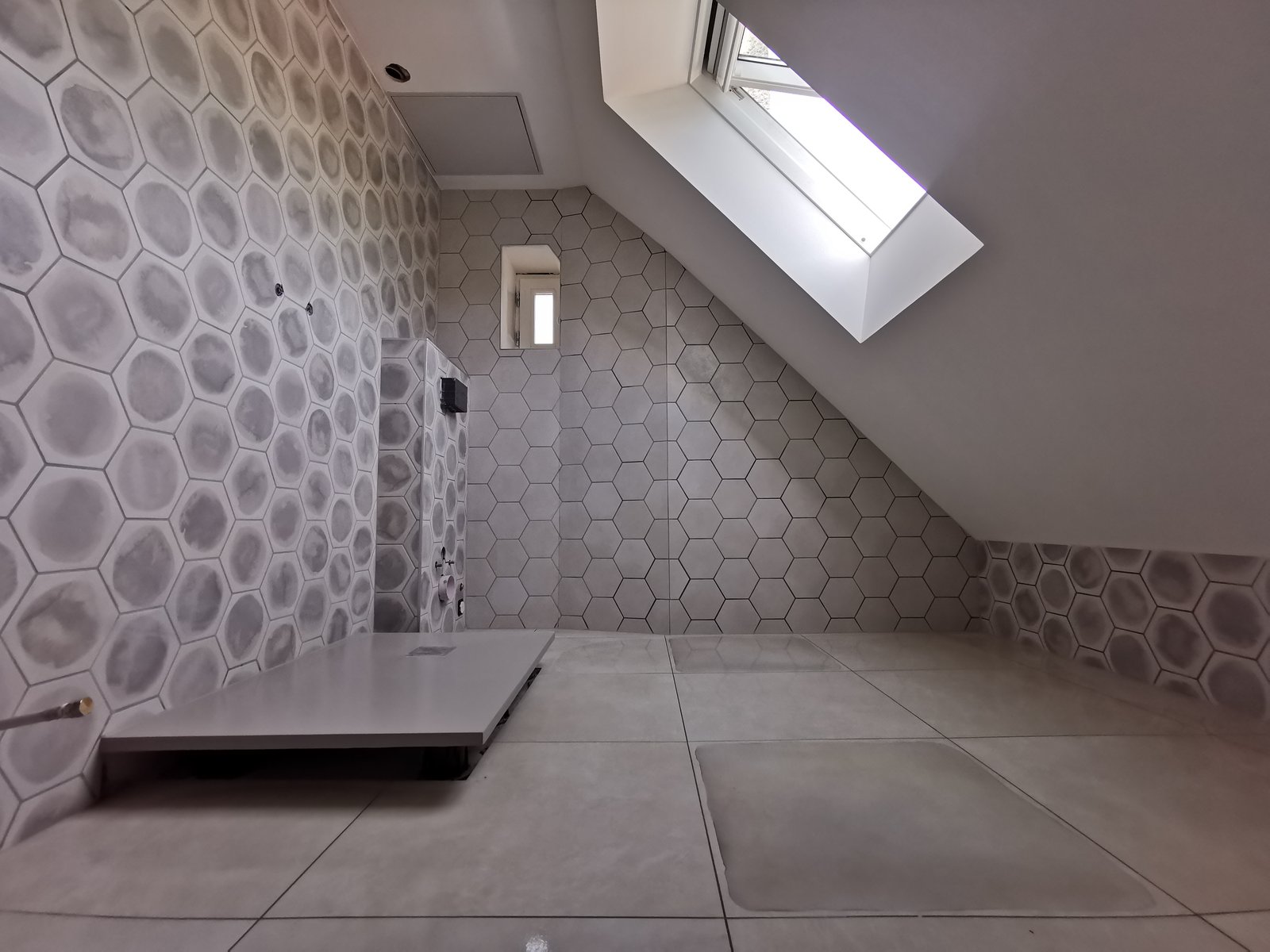 Salle de bain sous combles avec carreaux hexagonaux et receveur de douche grand format