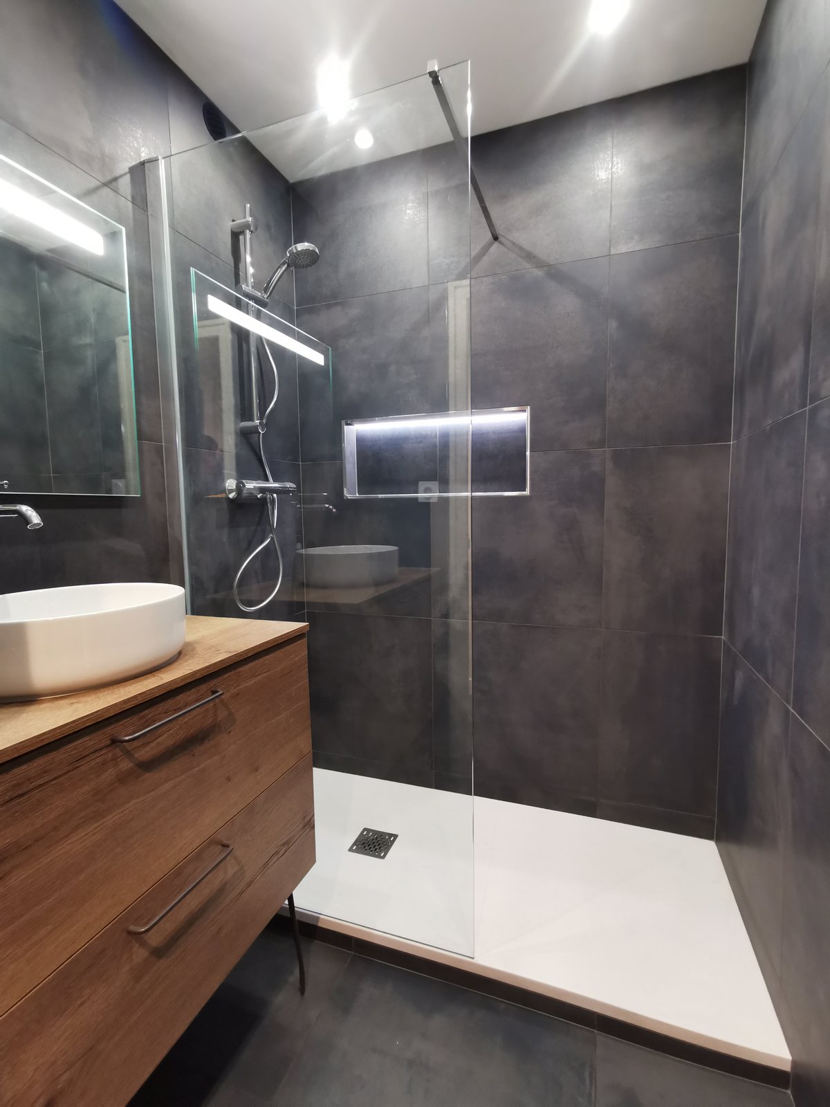 Salle de bain moderne en marbre avec meuble en bois clair et douche grand format gris foncé