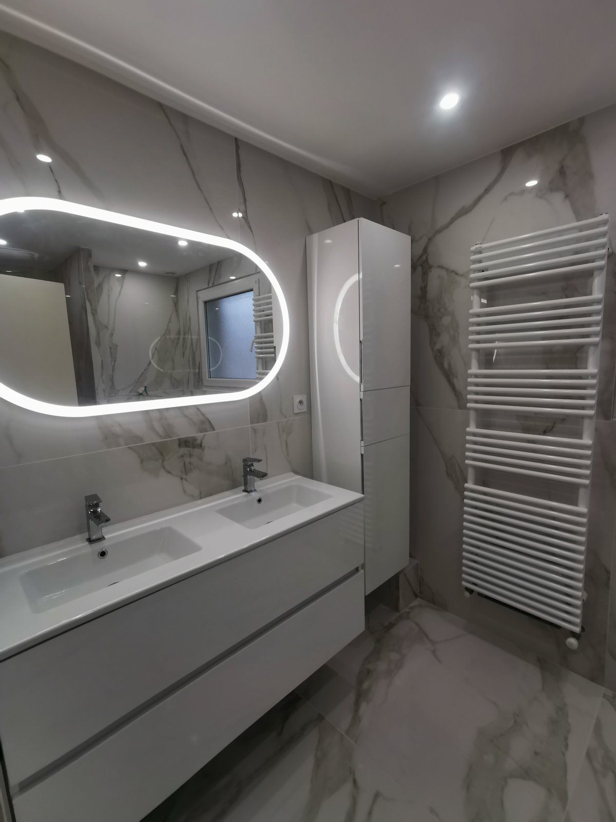 Vasque double avec grand miroir arrondi LED dans une salle de bain en marbre blanc