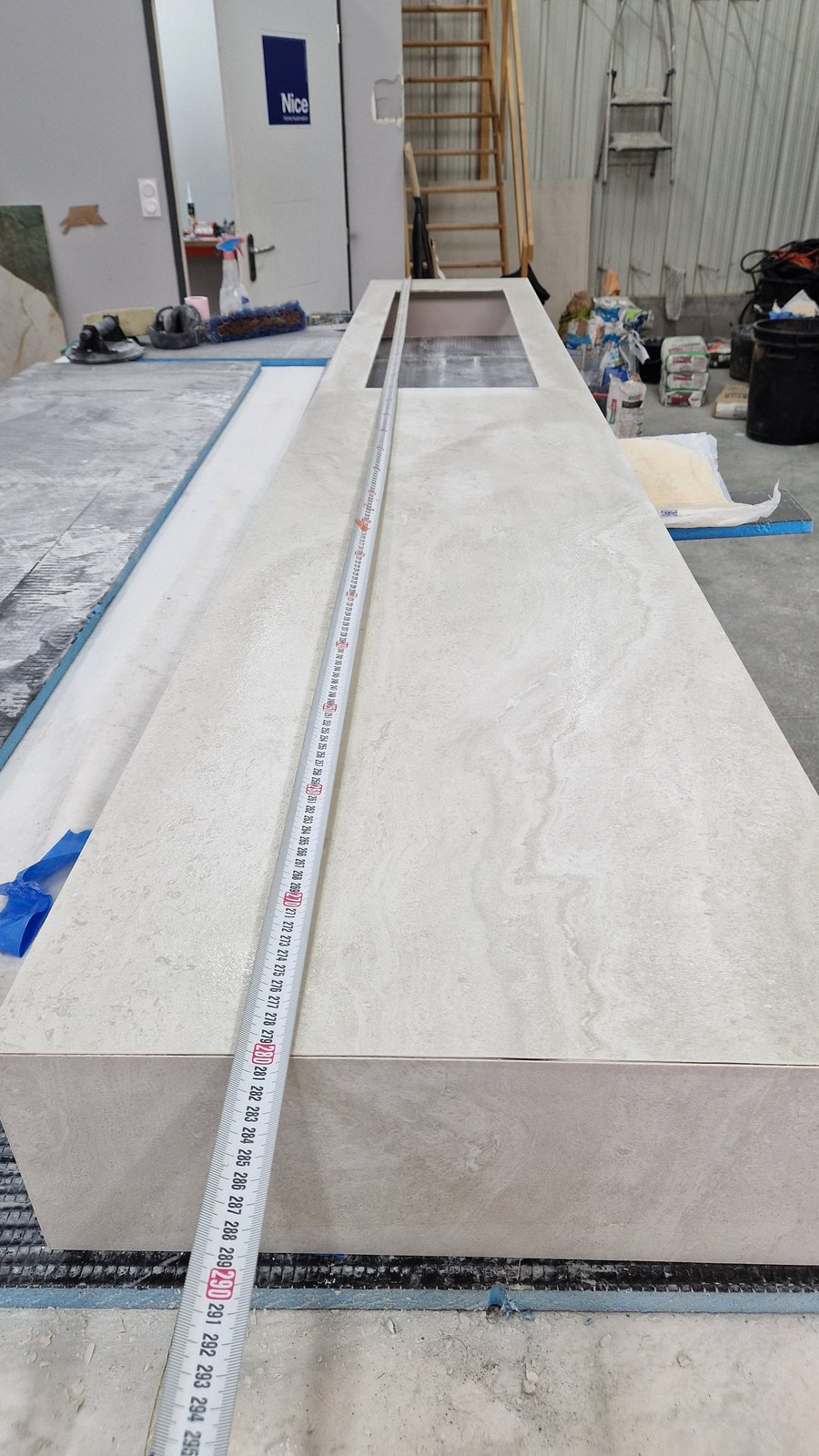 Vasque en carrelage format long en grès cérame effet travertin, exploitant toute la largeur de la pièce