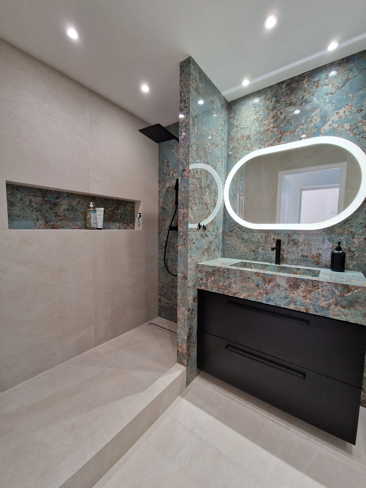 Vasque en carrelage marbre bleu Florim installée en salle de bain avec miroir LED en arche et meuble noir